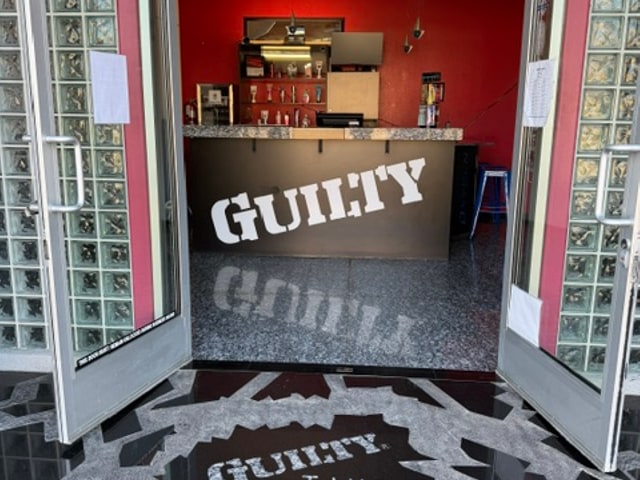 The Guilty Tans front desk in Cathedral City, with granite floors and the salon's branded counter
